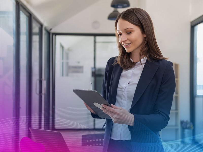 A stylish white businesswoman in a black suit standing inside the office in hands with a mobile phone